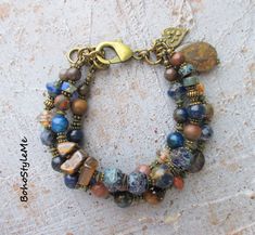 Stone Mountain, Boho Style Me, Rustic Beaded Gemstone Bracelet, Bohemian Jewelry, BohoStyleMe, Modern Hippie Chic  Deep, dark blues and browns are the perfect setting for this rustic gemstone nature bracelet. Mixed gemstones, including lapis lazuli, mixed jaspers, iron stone, tiger eye and Mashan jade are coupled with Picasso glass beads. This mountain night beaded bracelet is finished with a beautiful stone teardrop bead and bohemian charm. Antiqued brass is used throughout this earthy boho bracelet - enjoy! Length - 7 1/2 inches  Please see all pictures for accurate colors. Created for you - my unique handcrafted jewelry is created individually in my personal design studio in Dubuque IA USA. Each, and every, design I produce is made with love and the highest quality materials available t Boho Beaded Bracelets, Mountain Night, Blues And Browns, Dubuque Iowa, Iron Stone, Homemade Bracelets, Earthy Jewelry, Modern Hippie, Unique Handcrafted Jewelry