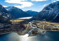 an aerial view of a small town surrounded by mountains and water in the foreground