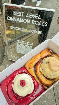 a box filled with different types of pastries on top of a sidewalk next to a sign