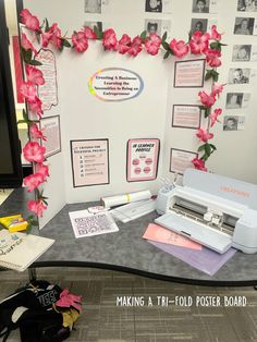 a table with some pink flowers on it and a white machine in front of the wall