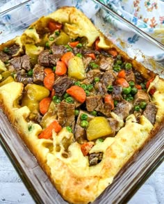 a casserole dish with meat, vegetables and potatoes in it on a table