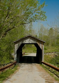 a small wooden covered bridge over a dirt road