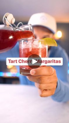 a man is holding up a drink in his hand and the caption reads tart cher margaritas