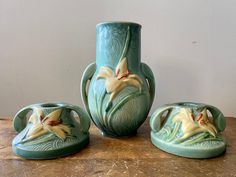 three green vases sitting on top of a table next to each other with flowers painted on them