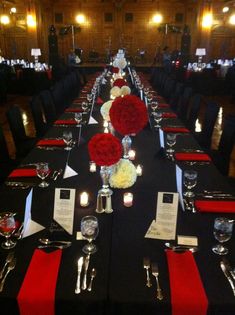 a long table is set up with black linens, red and white centerpieces