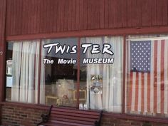 the front window of a movie museum with an american flag in the window and another sign that reads twister