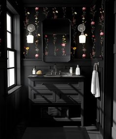 a black and white bathroom with floral wallpaper on the walls, sink and mirror