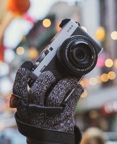 a person holding up a camera to take a picture in the street with it's mittens on