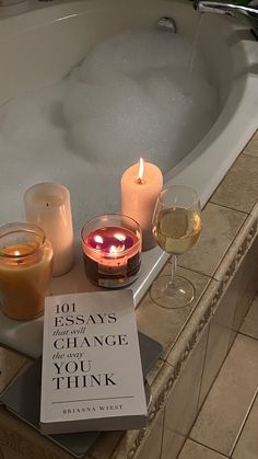 a book and two glasses of wine on a bathtub