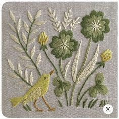 a yellow bird sitting on top of a white cloth next to flowers and leaves with green stems