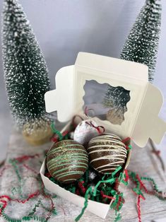 some chocolates are in a box with christmas decorations on the table next to them