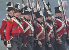 men in red uniforms and black hats are marching