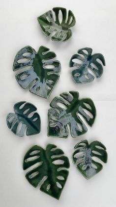 four green leaf shaped dishes sitting on top of a white table