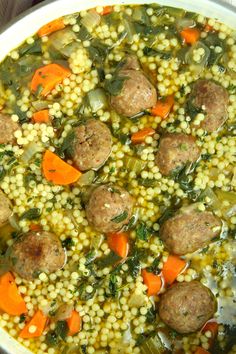 a bowl filled with meatballs, carrots and couscouse on top of a table