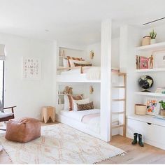 a bedroom with white walls and shelves filled with books, plants and other things on top of it