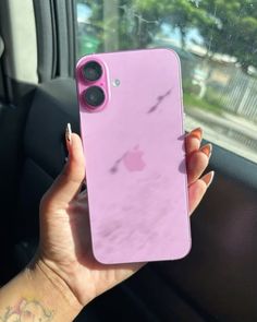 a woman is holding up her pink iphone case in the back seat of a car