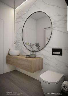 a white bathroom with a round mirror above the sink and toilet in front of it