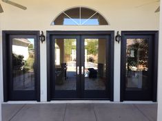 the front entrance to a house with double doors and windows on both sides, facing an outdoor patio