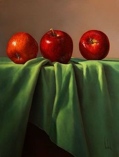 three apples sitting on top of a green cloth