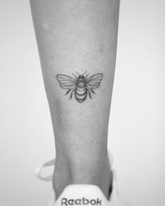 a black and white photo of a bee tattoo on the leg by radbok