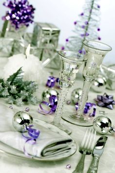 the table is set with silver and purple decorations