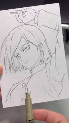 someone is holding up a drawing with a pen in front of their face and hand