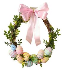 an easter wreath with painted eggs and greenery on the front, tied with a pink ribbon