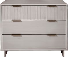 a white dresser with three drawers and two brass pulls on the bottom drawer, against a white background