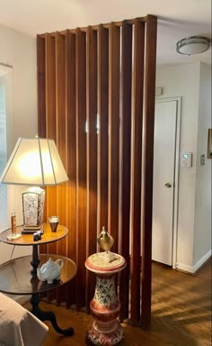 a room with a lamp, table and wooden slats on the wall