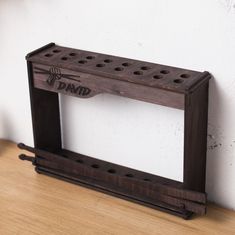 a wooden rack with holes in the middle on a wood floor next to a white wall