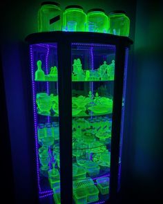 a lighted display case filled with lots of green items in the dark, lit up by neon lights