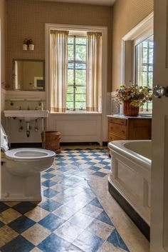 a bathroom with blue and white checkered flooring next to a bathtub in the corner