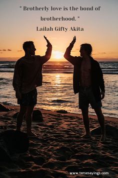 two men standing on top of a beach next to the ocean with a sunset in the background