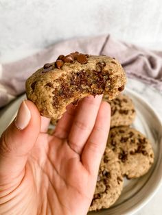 a person holding up a cookie on a plate