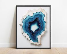 an abstract piece of art with blue and white colors on the surface in a black frame