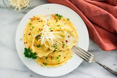 a white plate topped with pasta covered in cheese and parmesan sprinkles