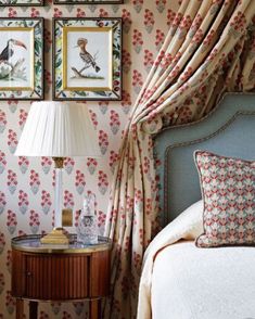 a bedroom with floral wallpaper and pictures on the wall