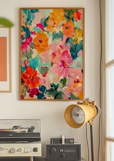 an old record player sitting on top of a table next to a painting and lamp