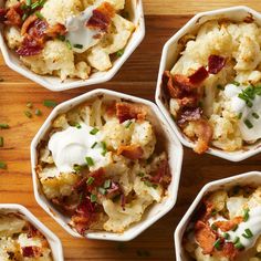 four white bowls filled with different types of food on top of a wooden table and topped with sour cream