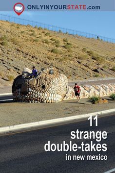 two men are standing next to a large rock sculpture on the side of a road