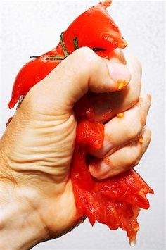 a hand holding up a piece of tomato