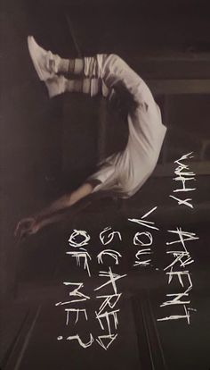 a man doing a hand stand in front of a wall with writing written on it