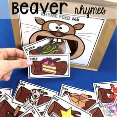 a hand holding up some cards with pictures of beaver and cake on them, in front of