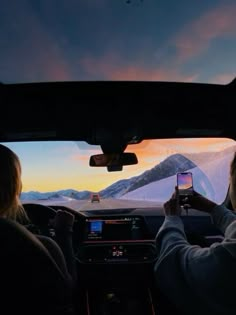 two people sitting in the back seat of a car while looking at a cell phone