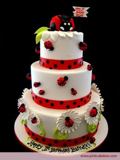 a three tiered cake with ladybugs and daisies on the bottom layer