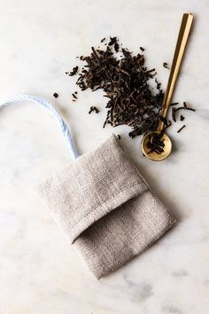 a tea bag next to a spoon and some loose leaves on a marble table top