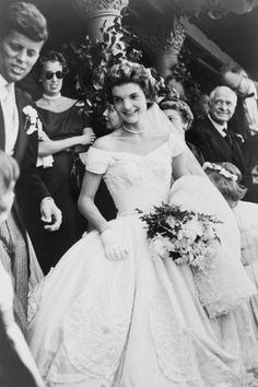 an old black and white photo of a woman in a wedding dress standing next to a man