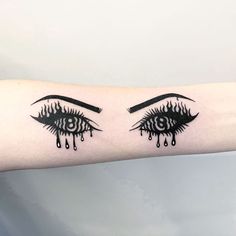 two black and white tattoos on the arm of a woman's left arm, with dripping eyes