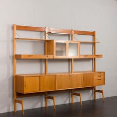 a wooden shelf with drawers and shelves on the top, against a wall in an empty room