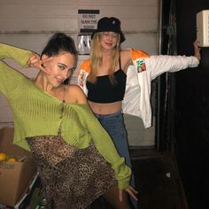 two young women standing next to each other in front of a garage door with their arms around one another